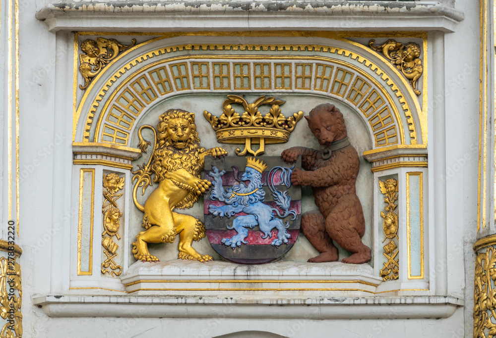 Bruges, Flanders, Belgium -  June 16, 2019: Coat of arms of the city with gold, blue, white, black and brown images of lion and bear. Set in facade.
