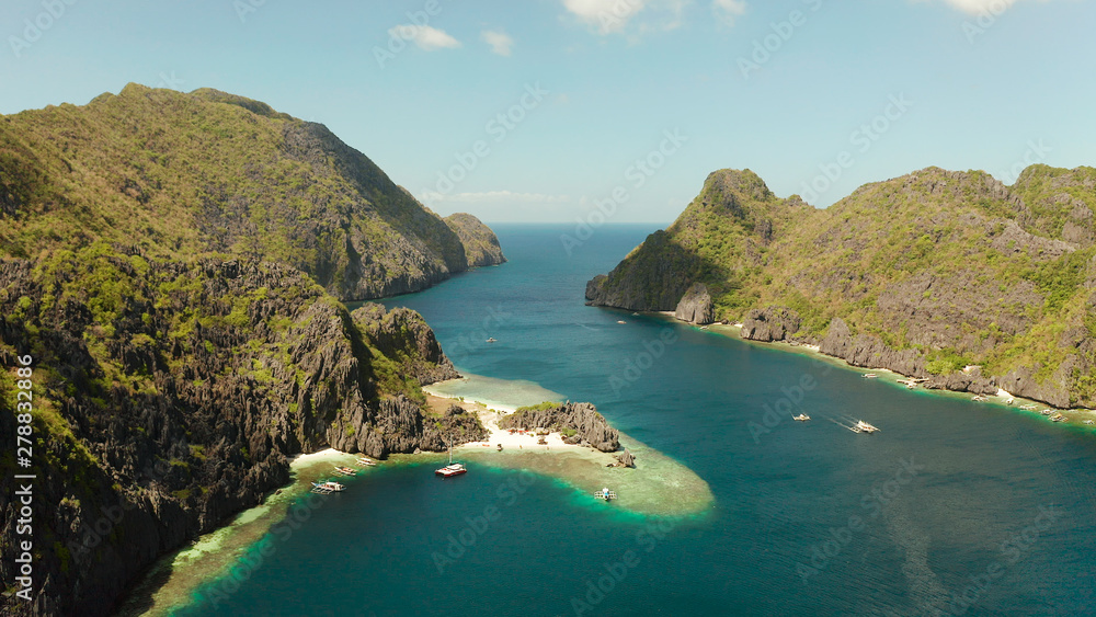 Tropical lagoon with sandy beach surrounded by cliffs, aerial view. El nido, Philippines, Palawan. Seascape with tropical rocky islands, ocean blue water. Summer and travel vacation concept