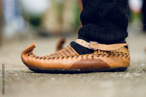 Close up on man feet wearing Serbian National Folk Folklore costume footwear Opanak or opanci on the homemade woolen socks standing outdoor in a day photo