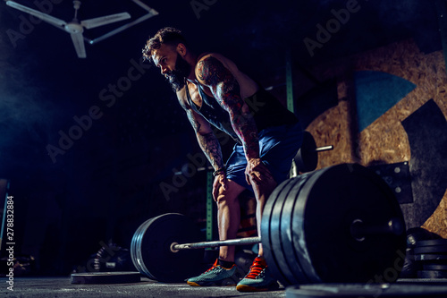 Muscular fitness man preparing to deadlift a barbell over his head in modern fitness center. Functional training. Snatch exercise