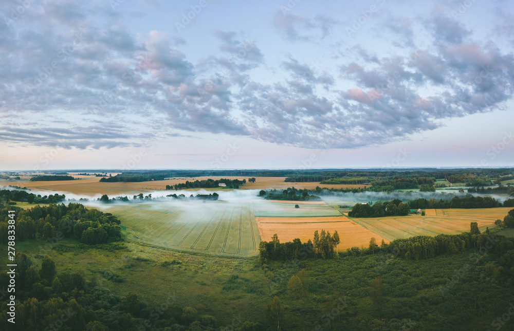 Aerial view over a misty morning over countryside. Fog covering the crop fields and river. Colorful sunrise over the fields and forest. Aerial view over a misty morning over countryside. Fog covering the crop fields and river. Colorful sunrise over the fields and forest.