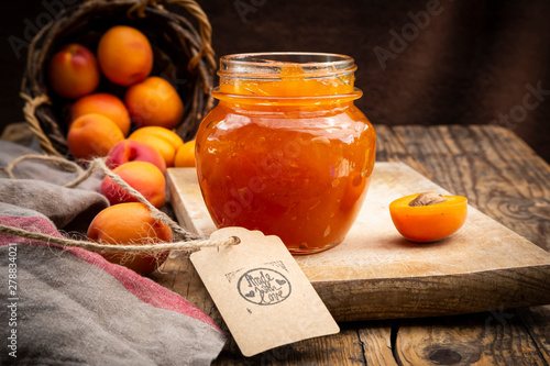 Apricot jam and apricots, sign 'made with love' on dark wood photo
