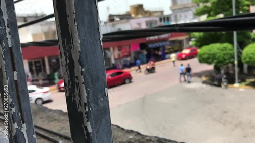 Wallpaper Mural View of a street from a balcony with rusted and dirty iron in the foreground and cars and people on the background Torontodigital.ca