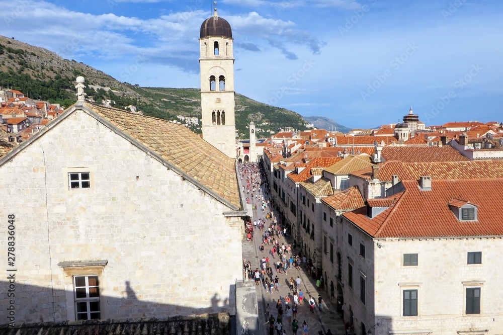 A great view of the old town in Dubronvik Croatia from the perspective of the walls of Dubronvik. The view looks down on Stradun Street full of tourists walking around on a busy summer day