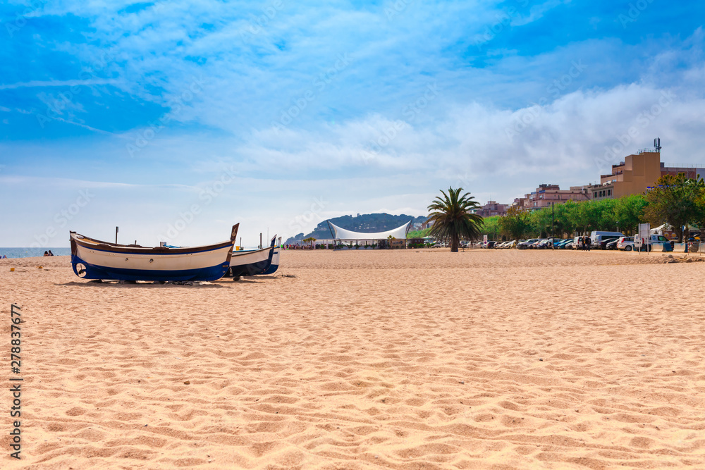 Fototapeta premium Beach at seaside in Calella in Catalonia, Spain near Barcelona. Scenic old town with sand beach and clear blue water. Famous tourist destination in Costa Brava, perfect place for holiday and vacation