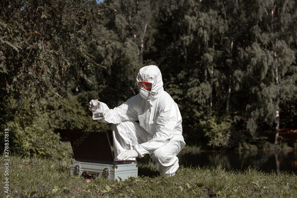 Ecological problem. Pollution. Examine oxygen. Scientist in protective mask and suit taking water samples from river. Chemist makes an analysis of the environment for radiation. Ecological problem. Pollution. Examine oxygen. Scientist in protective mask and suit taking water samples from river. Chemist makes an analysis of the environment for radiation.