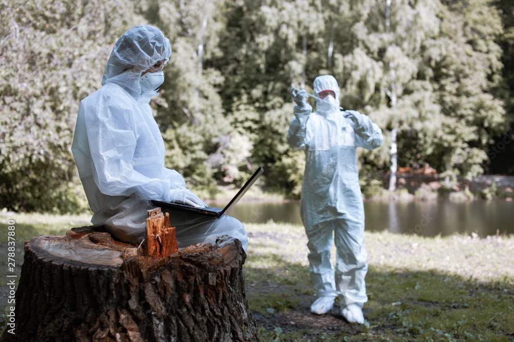 Ecological problem. Pollution. Examine oxygen. Scientist in protective mask and suit taking water samples from river. Chemist makes an analysis of the environment for radiation. Ecological problem. Pollution. Examine oxygen. Scientist in protective mask and suit taking water samples from river. Chemist makes an analysis of the environment for radiation.