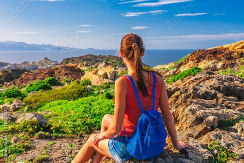 Tourist woman with backpack on Cap de Creus, natural park. Eastern point of Spain, Girona province, Catalonia. Famous tourist destination in Costa Brava. Sunny summer day with blue sky and clouds photo