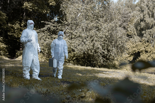 Ecological problem. Pollution. Examine oxygen. Scientist in protective mask and suit taking water samples from river. Chemist makes an analysis of the environment for radiation.  © Anton Gepolov