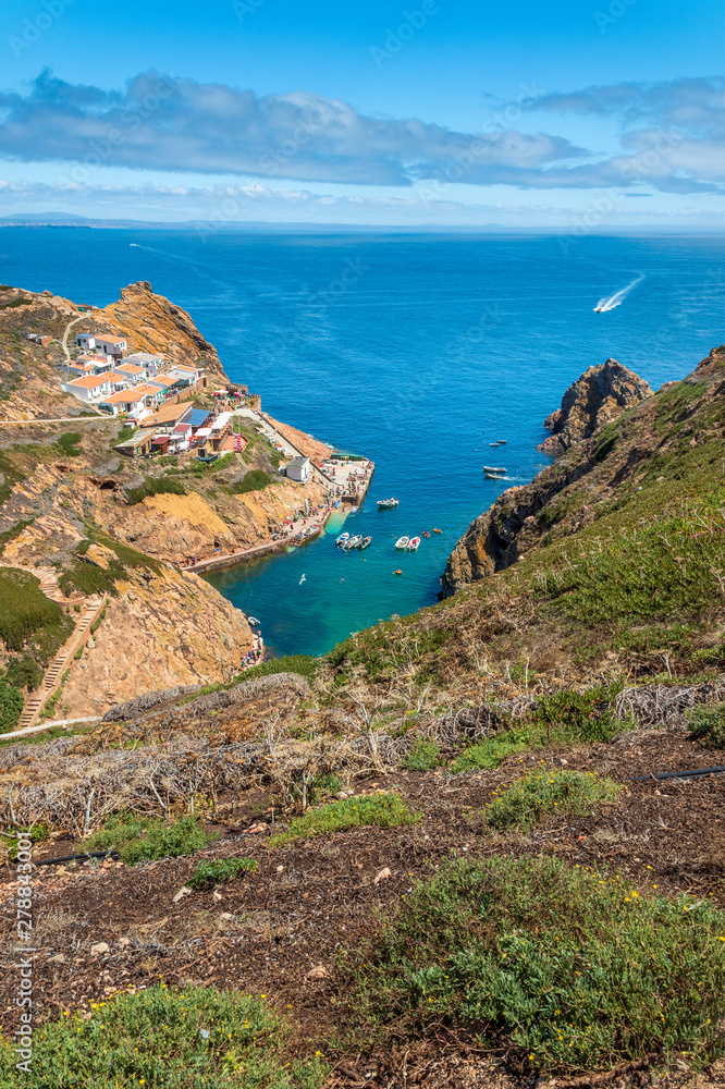 View of the Fisherman's Quarter, anchorage and cove with boats anchored on the island of Berlenga, Portugal, with the horizon and coast of mainland Portugal in the background.