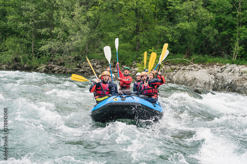 Group of people rafting in rubber dinghy on a river