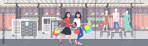 women carrying shopping bags girls couple having fun walking together holiday big sale concept modern boutique fashion shop exterior flat full length horizontal banner