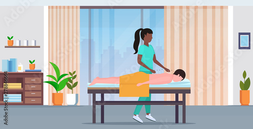 african american acupuncturist holding needle man patient getting acupuncture treatment treatments alternative medicine concept modern spa salon interior full length horizontal