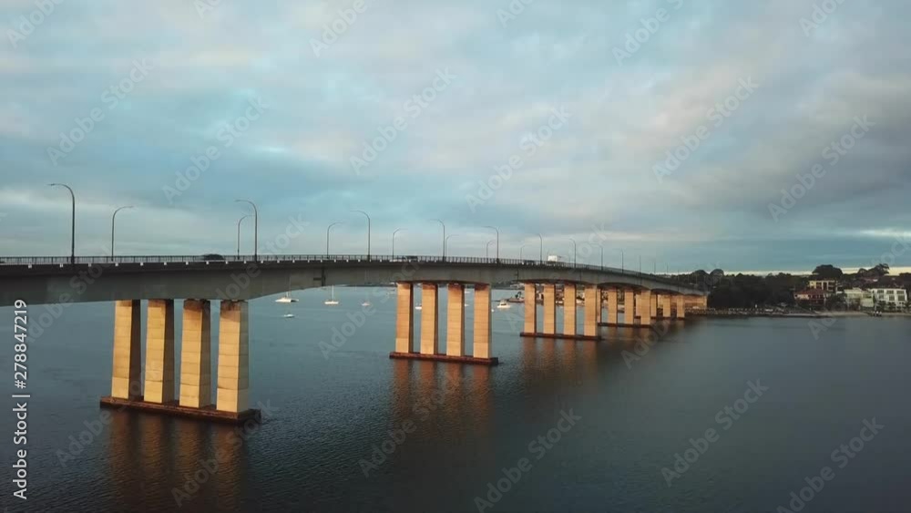Aerial: Drone shot slowly rising to reveal traffic driving over a large bridge whilst commuting to work during morning rush hour in Sydney, Australia. Aerial: Drone shot slowly rising to reveal traffic driving over a large bridge whilst commuting to work during morning rush hour in Sydney, Australia.