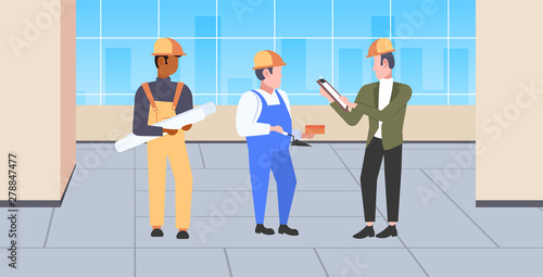 construction workers team discussing new building project during meeting mix race builders in helmet industrial technicians teamwork concept modern office interior full length horizontal