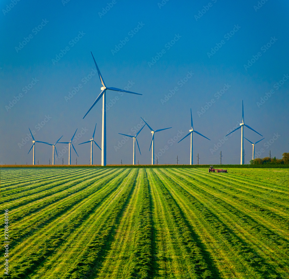 Tractor farming under large wind turbines. Stock Photo Adobe Stock