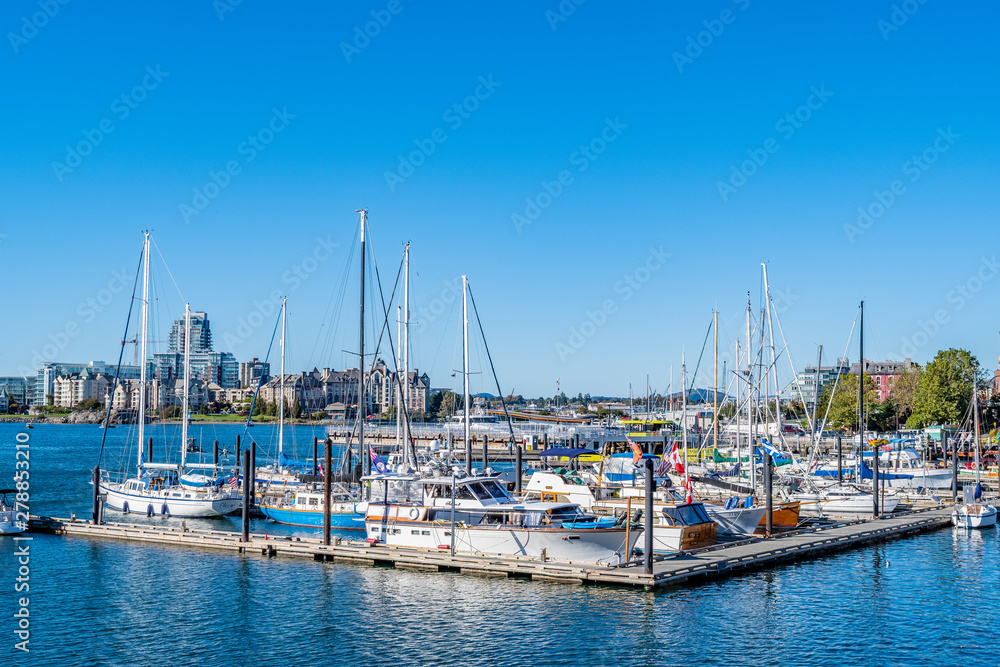 Boats and yachts moored in the Inner Harbour downtown with buildings in the background. A view of the city of Victoria's popular tourism and business district.