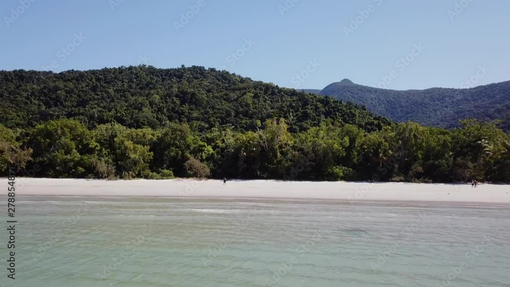 Aerial: Drone moving away from a lone figure standing on a white sandy beach to slowly reveal more of the stunning landscape, in Cape Tribulation, Far North Queensland. Aerial: Drone moving away from a lone figure standing on a white sandy beach to slowly reveal more of the stunning landscape, in Cape Tribulation, Far North Queensland.