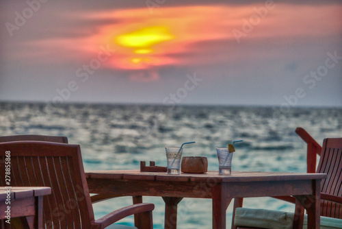 This unique photo shows a romantic abandoned space with empty glassware at a sunset. the photo was taken in the maldives