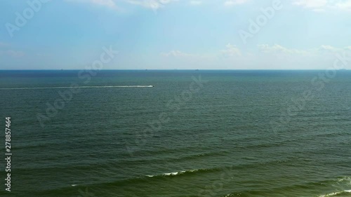 aerial shot over the ocean in Long Beach, New York as a fast boat moves off in the distance towards the right photo