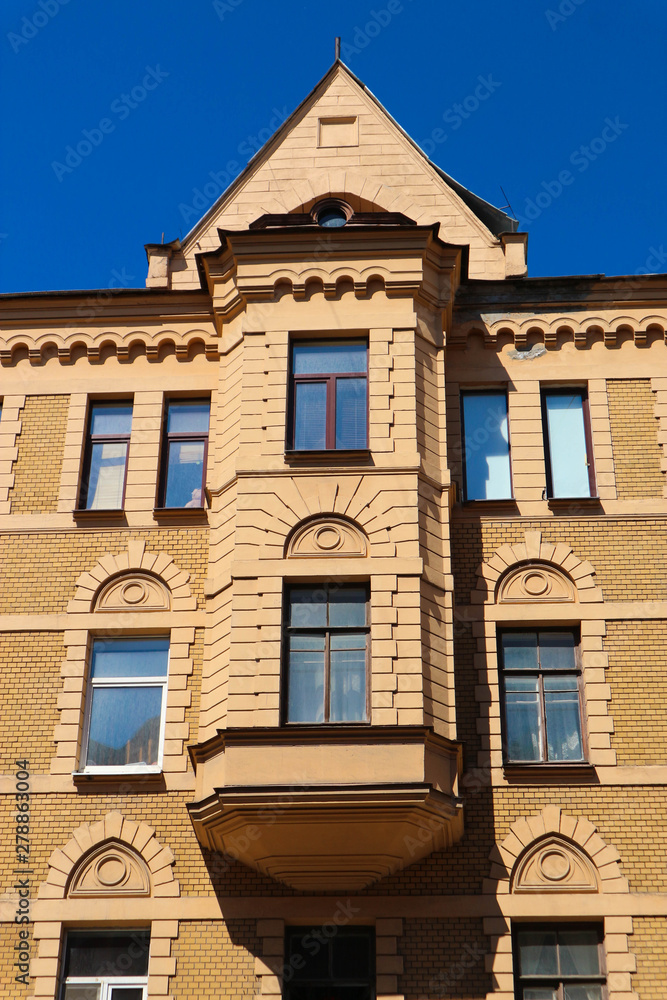 Obraz premium Facade of beautiful old yellow house with bay window in downtown of Saint Petersburg Russia with blue sky on the background