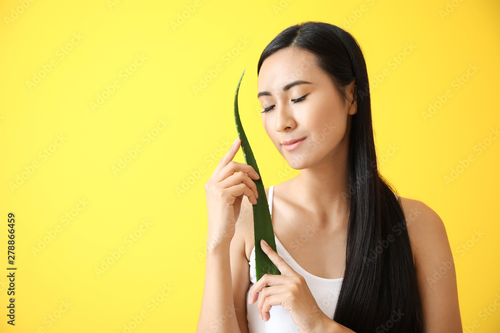 Beautiful Asian woman with aloe vera on color background Beautiful Asian woman with aloe vera on color background