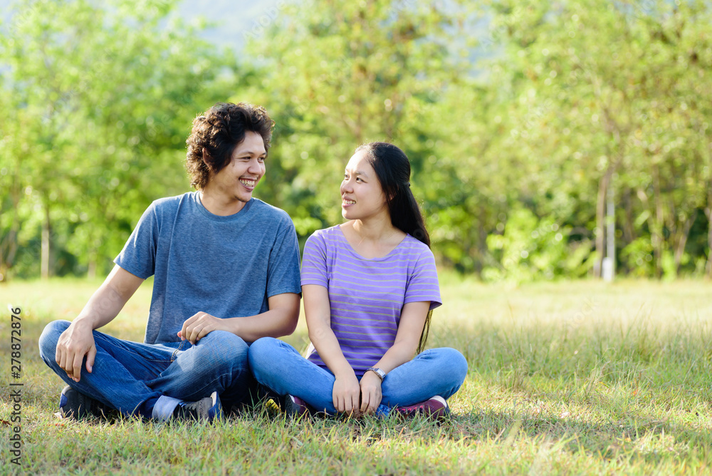 Happy Asian couple sitting on green grass in outdoor Happy Asian couple sitting on green grass in outdoor