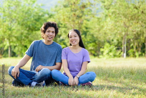 Happy Asian couple sitting on green grass in outdoor © nungning20