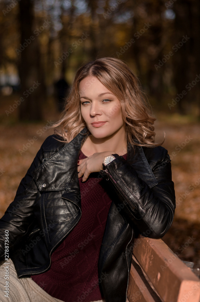 Portrait of a beautiful woman sitting on the bench in autumn park, leisure time on warm sunny day Portrait of a beautiful woman sitting on the bench in autumn park, leisure time on warm sunny day