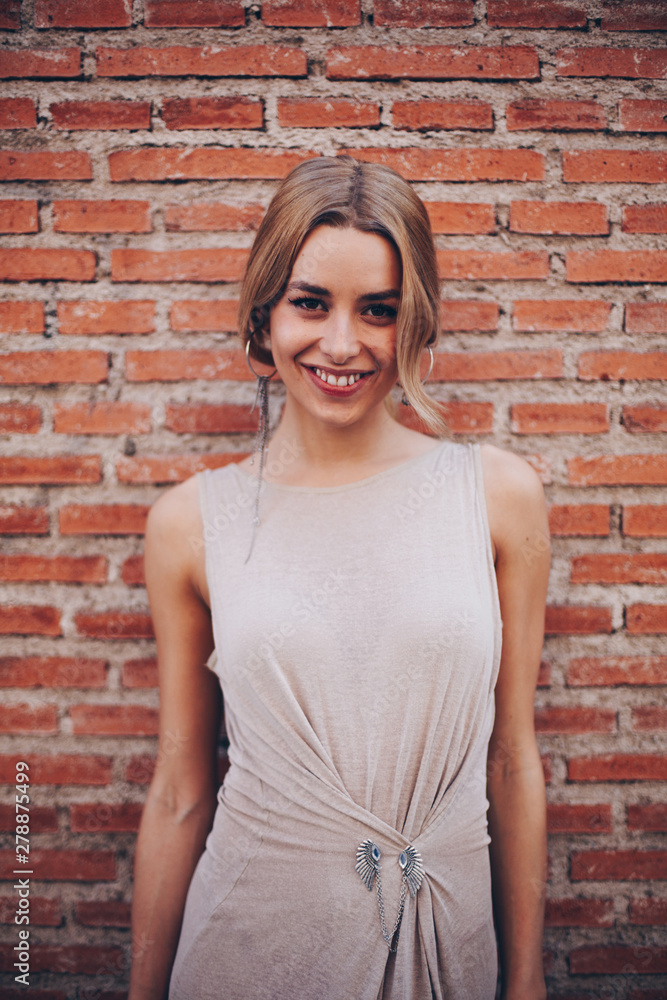 Portrait of blond woman standing in front of brick wall Portrait of blond woman standing in front of brick wall