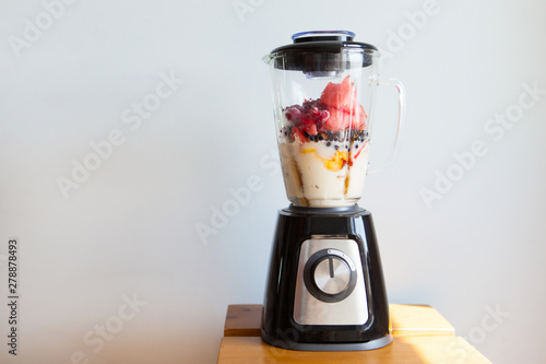 A blender filled with fresh whole fruits for making a smoothie or juice. Healthy eating concept.