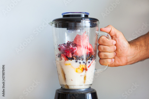 A blender filled with fresh whole fruits for making a smoothie or juice. Healthy eating concept. photo