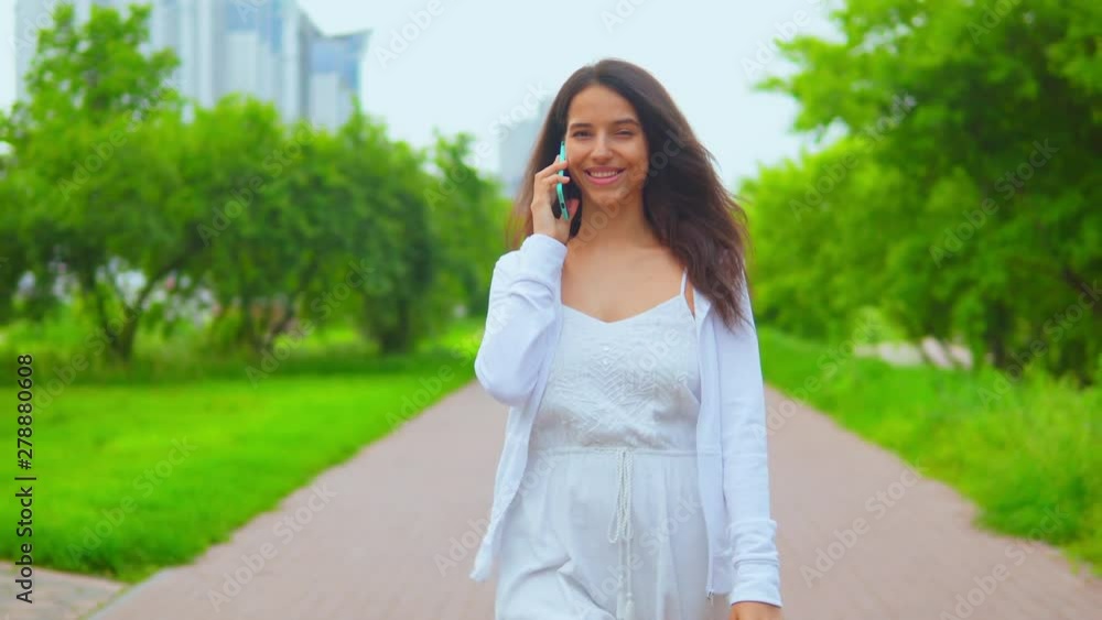 brunette woman walking has conversation by smartphone caucasian lady strolling in spring city brunette woman walking has conversation by smartphone caucasian lady strolling in spring city