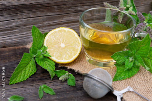 Hot peppermint tea with lemon on wooden background