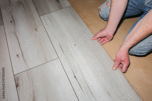 Worker making laminate flooring in apartment. Maintenance repair renovation. Wooden parquet planks indoors.