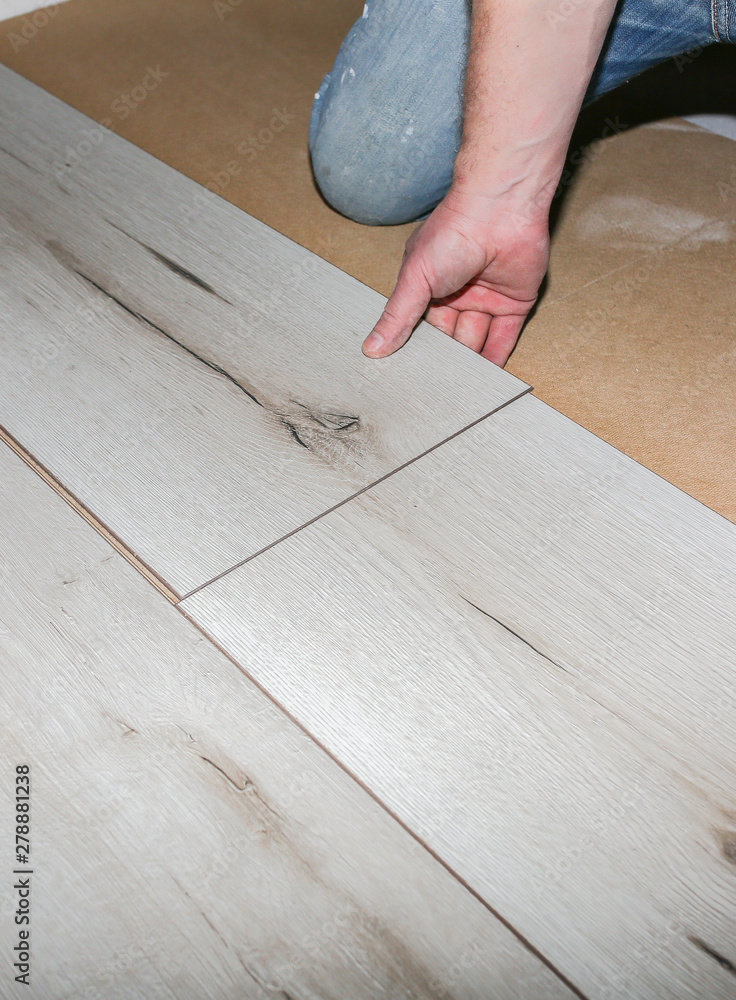 Worker making laminate flooring in apartment. Maintenance repair renovation. Wooden parquet planks indoors. Worker making laminate flooring in apartment. Maintenance repair renovation. Wooden parquet planks indoors.