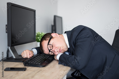 tired businessman sleeping on the table in modern office