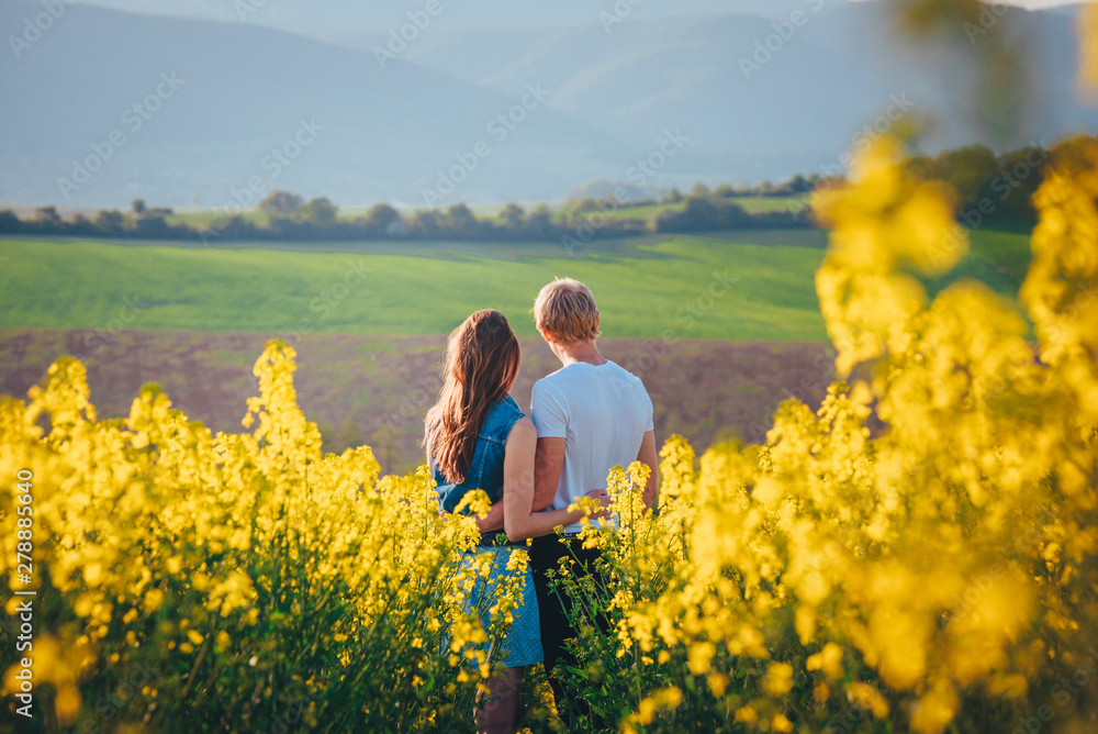 young couple in summer flower field with yellow flowers, rapeseed flower field in spring Germany