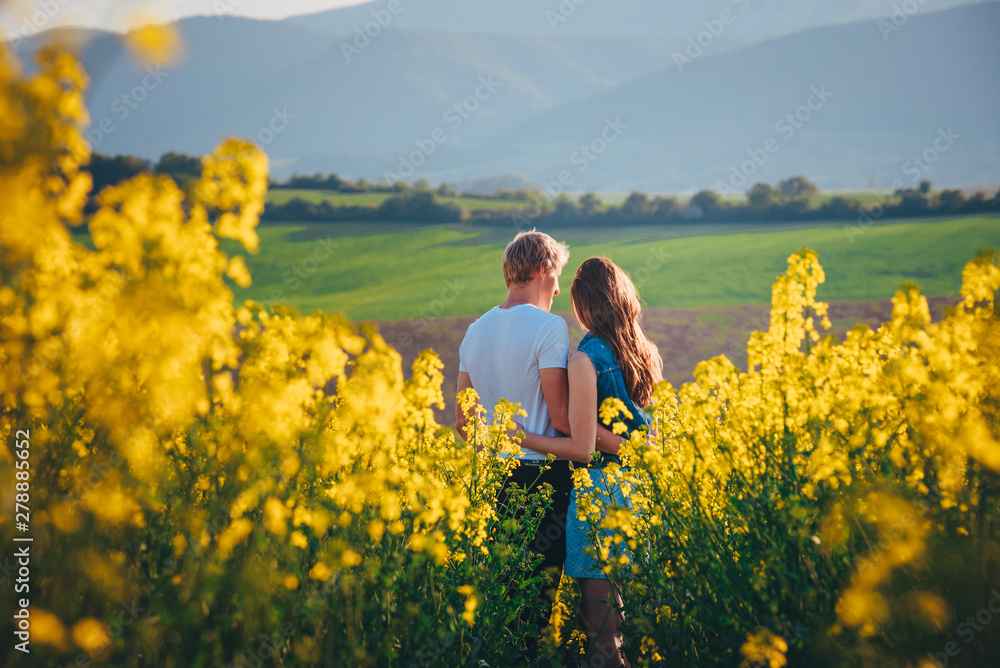 Couple hugging at sunset in yellow spring field. Romantic photo, white edit space Couple hugging at sunset in yellow spring field. Romantic photo, white edit space