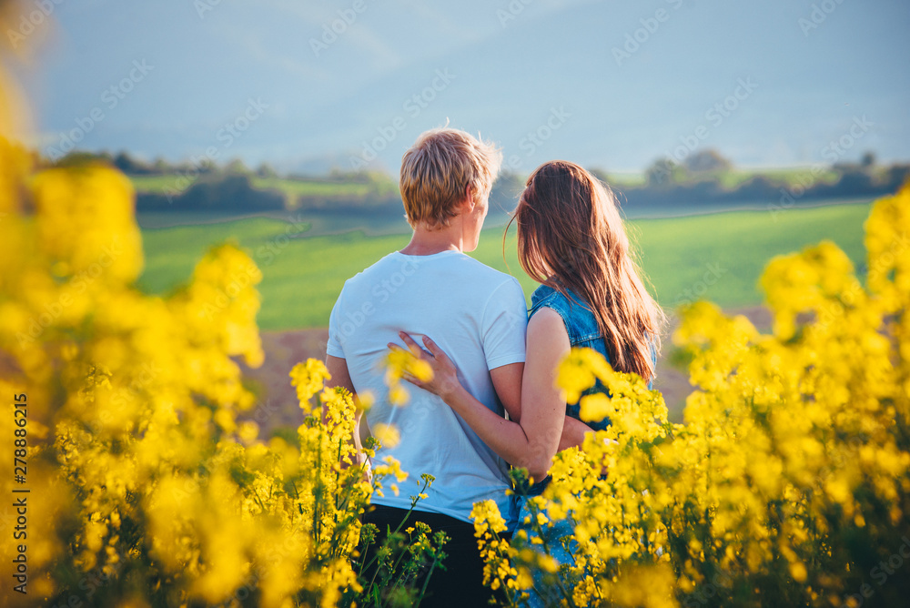 Couple hugging at sunset in yellow spring field. Romantic photo, white edit space Couple hugging at sunset in yellow spring field. Romantic photo, white edit space