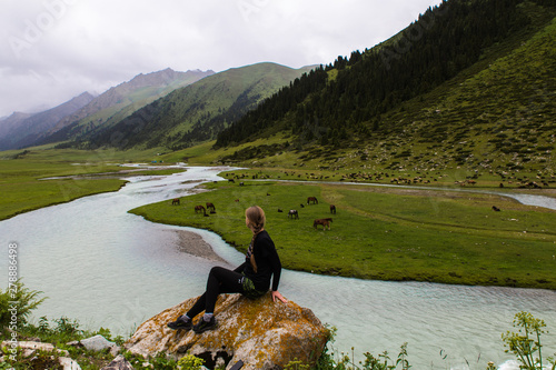 backwiev of the girl looking at Aksu river in Enilchek valley with green mountains in Kyrgyzstan photo