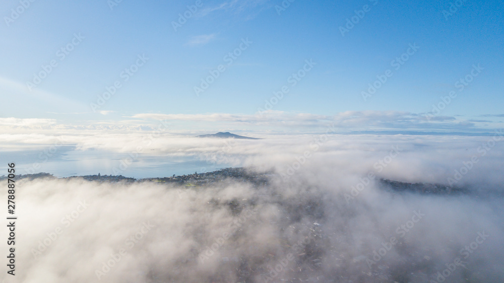 Aerial drone shot flying above the cloud, looking at the summit of Rangitoto Island.