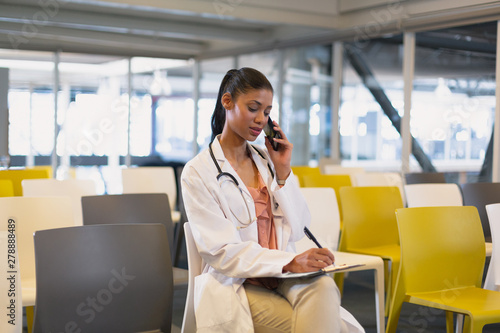 Wallpaper Mural Female doctor talking on mobile phone while writing on a clipboard  Torontodigital.ca
