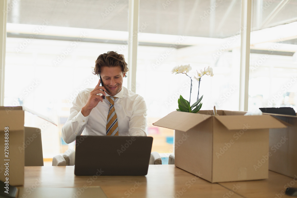 Businessman talking on mobile phone while using laptop in the conference room Businessman talking on mobile phone while using laptop in the conference room