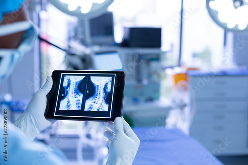 Surgeon examining x-ray on digital tablet in operating room of hospital