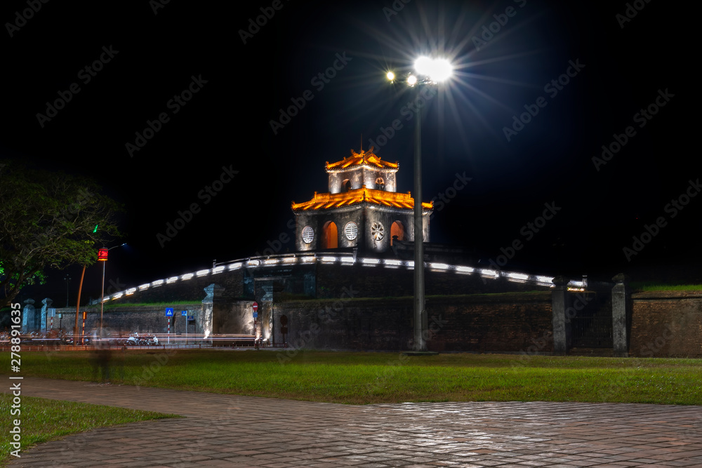 Tower and stone walls shimmering colors around the outside royal Imperial palace at night in Hue, Vietnam.