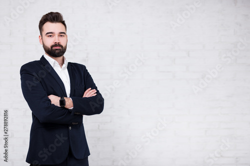 portrait of young bearded businessman over white brick wall background