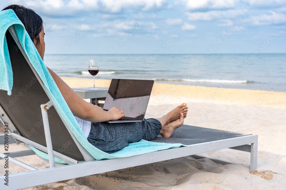 Freelance lady using laptop on the beach