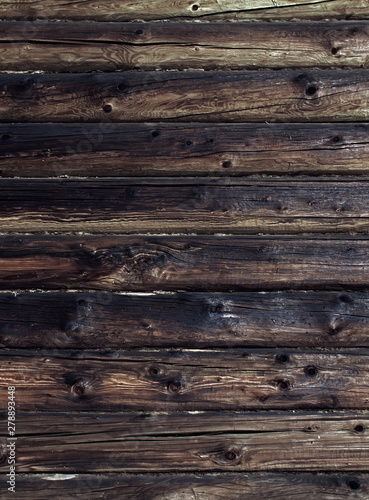 Old weathered log wall. Dark brown wooden background. Craked shabby logs.