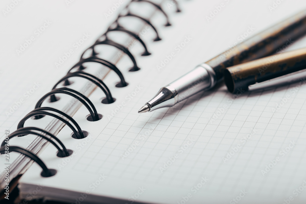Opened notepad in a cage with an automatic plastic ballpoint pen close-up. toned Opened notepad in a cage with an automatic plastic ballpoint pen close-up. toned